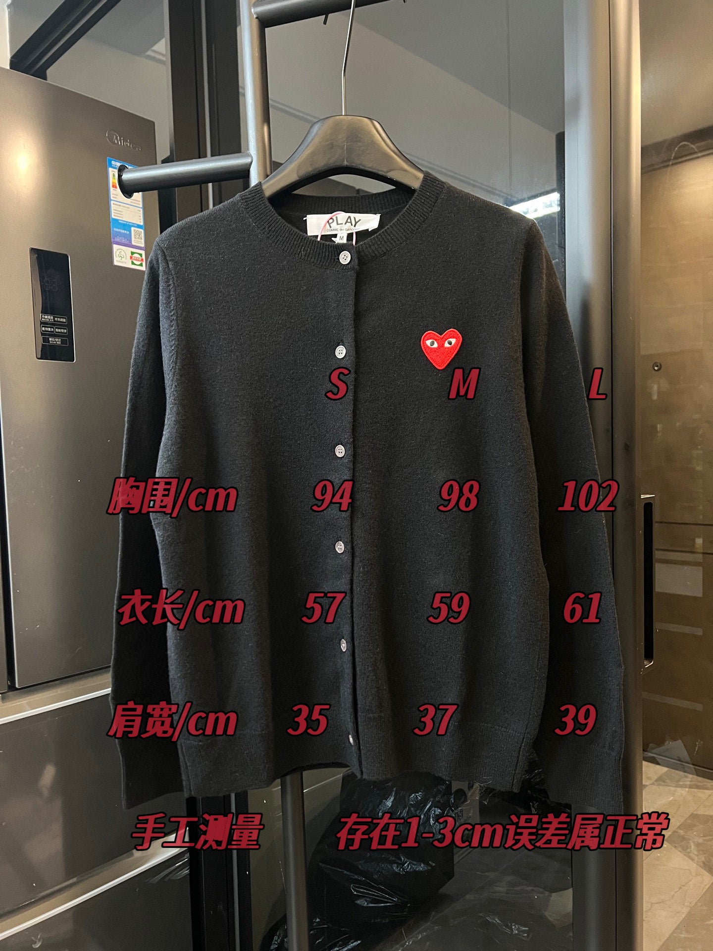 Amiri dark knit cardigan with red heart logo and red size measurement overlay.