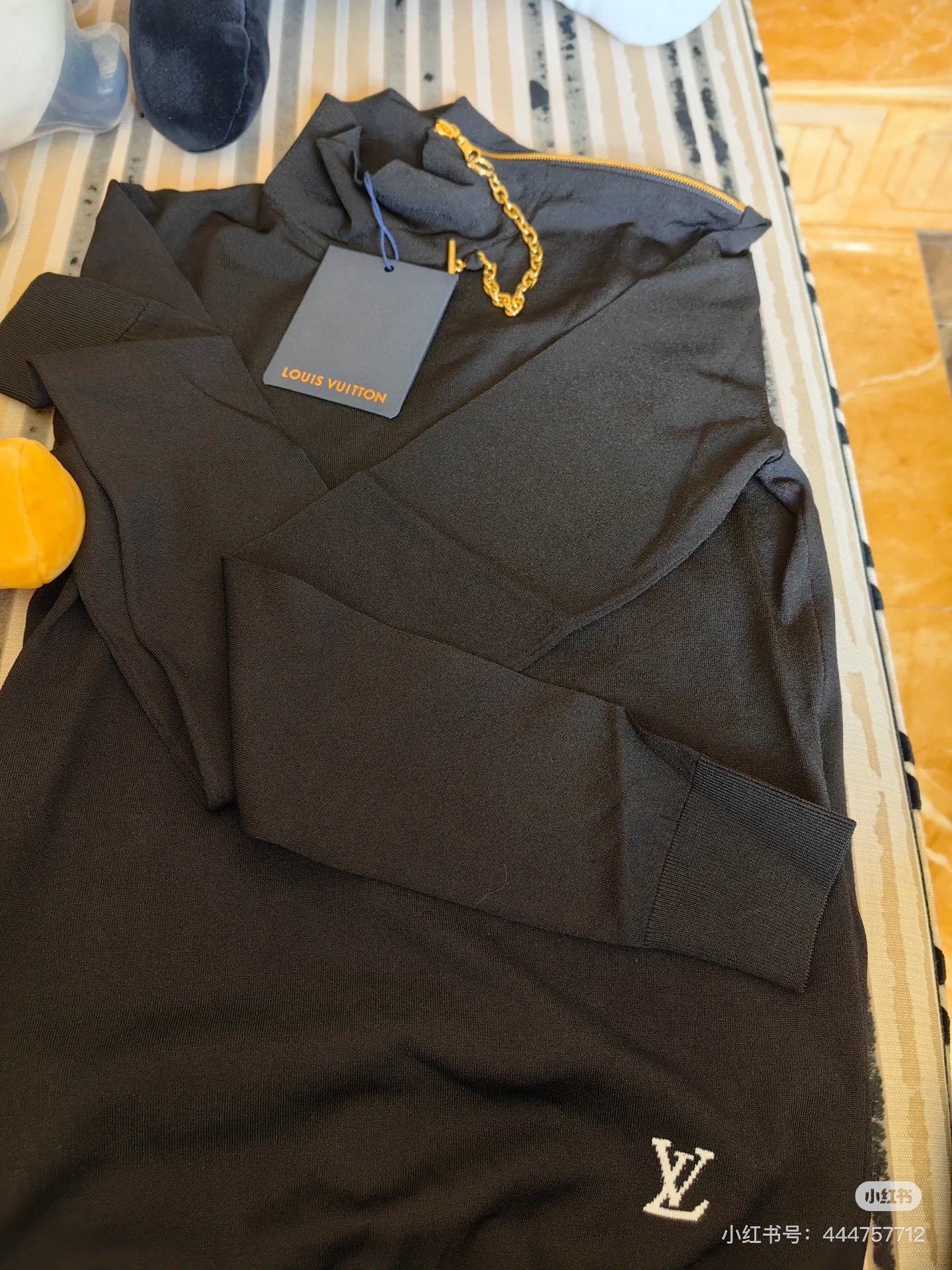 Louis Vuitton black long-sleeve pullover top, gold chain detail visible at neckline