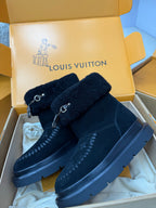 Dark navy Louis Vuitton high-top boots with shearling cuffs, buckle straps, and monogram print
