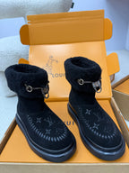 Dark navy high-top boots with shearling cuffs, metal buckles, and monogram-style detailing