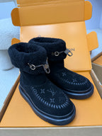Pair of dark navy high-top boots with fuzzy cuffs, metal buckles, and monogram pattern