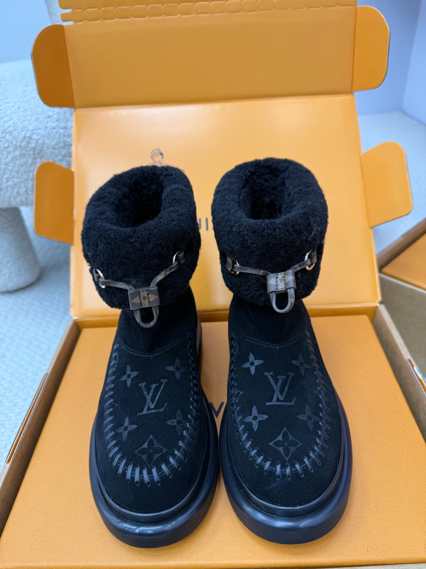 Dark navy Louis Vuitton high-top boots with shearling cuffs and buckle straps