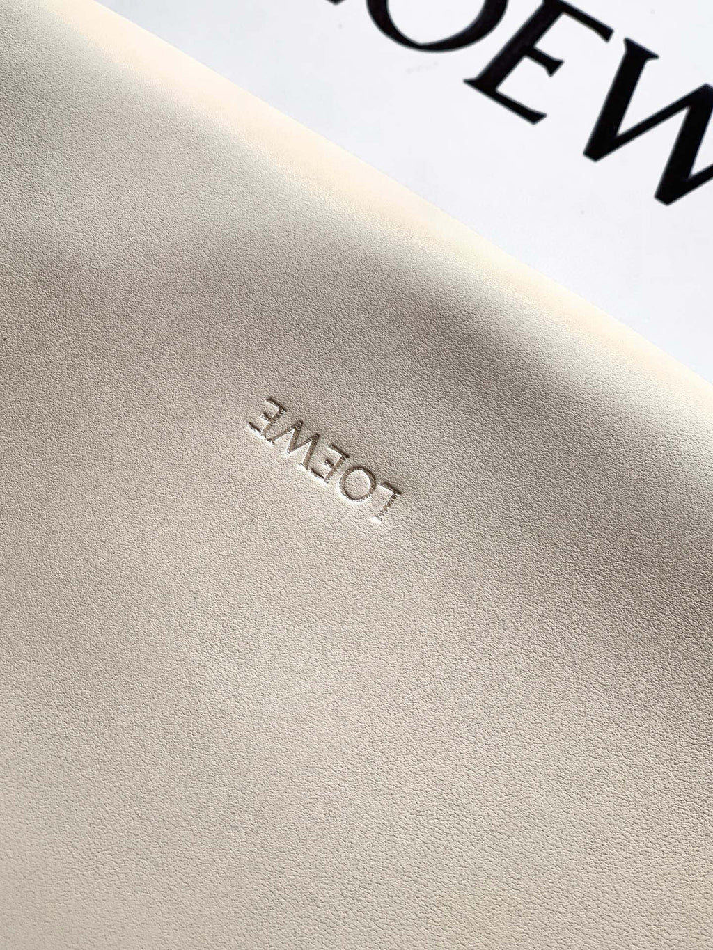 Leather fabric closeup with subtle embossed lettering on a cream surface