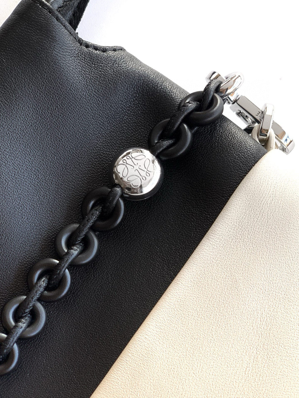 Loewe bag detail: black leather with metal clasp and braided chain link