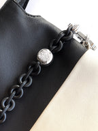 Loewe bag detail: black leather with metal clasp and braided chain link