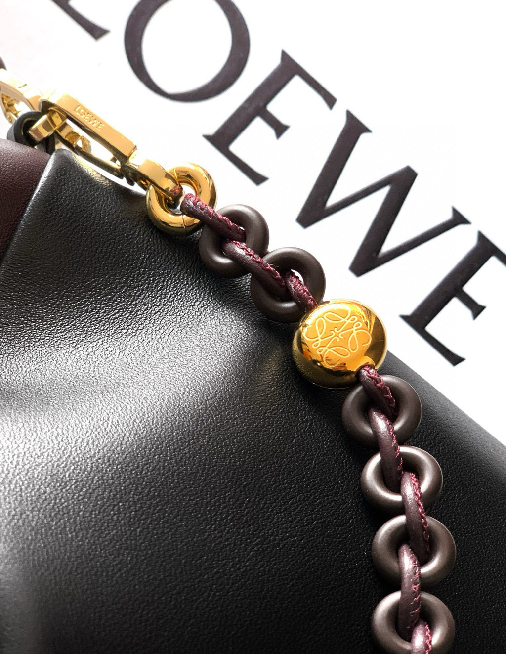 Leather bag close-up with gold hardware charm on braided cord strap