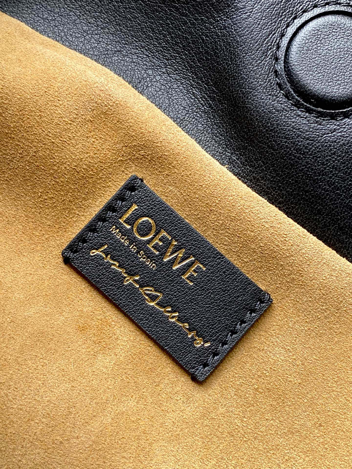 Loewe leather bag label on tan suede panel with embossed text