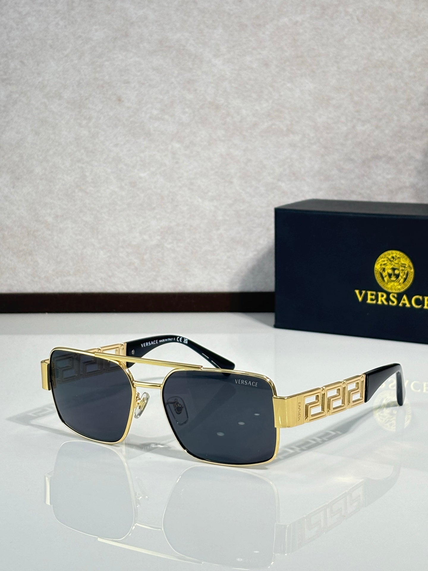 Sunglasses with gold-tone frames and dark blue lenses, geometric temple details