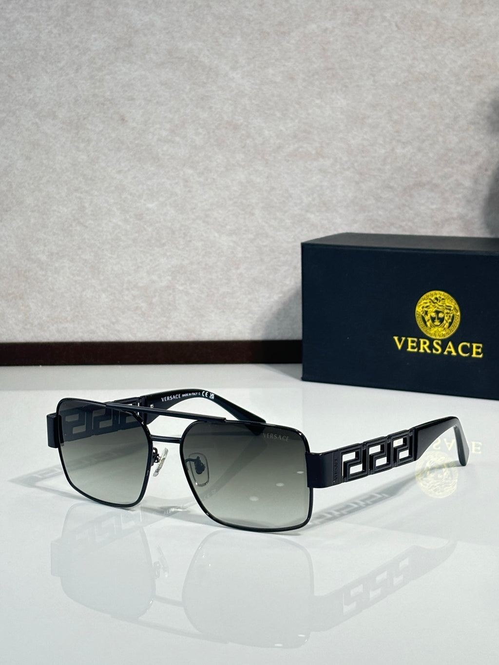 Sunglasses with black frames and dark gray lenses, gold Greek key temple details
