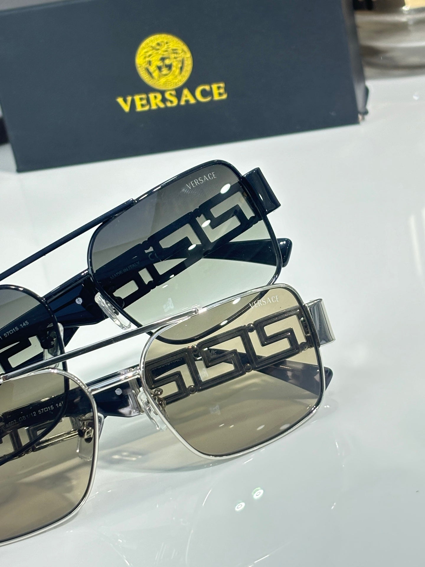 Sunglasses close-up with dark lenses and dark temples, metal Greek key accents
