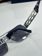 Sunglasses temple close-up with metal Greek key inlays and dark lens front