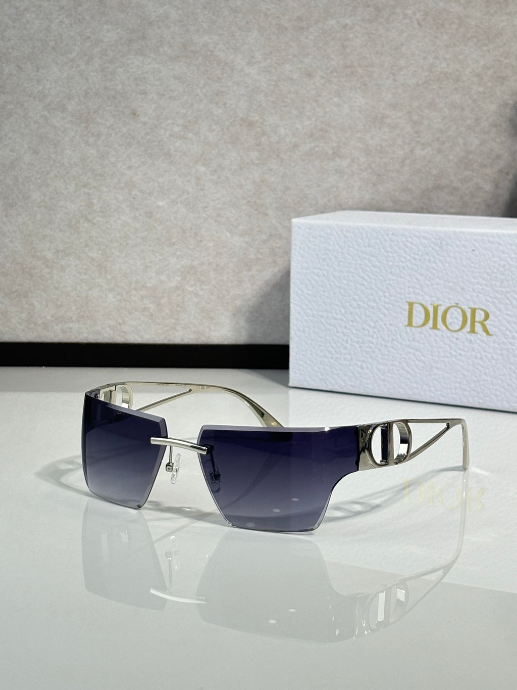 Dior sunglasses with gold frame and deep blue lenses, front three-quarter view.