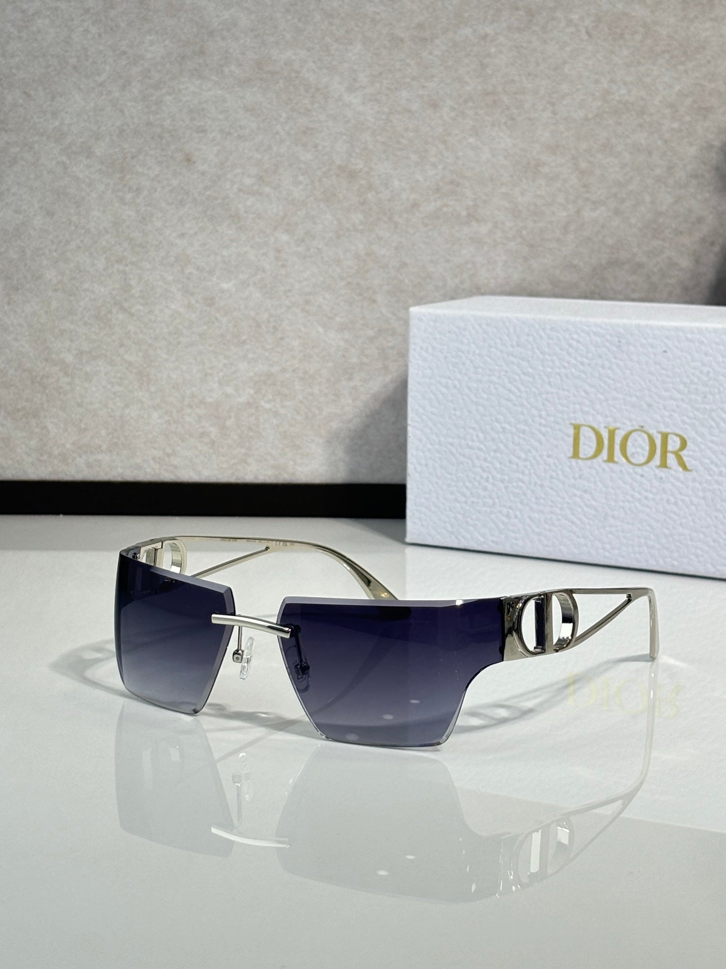Dior sunglasses with gold frame and deep blue lenses, front three-quarter view.