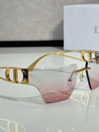 Dior sunglasses close-up of gold frame and pink gradient lenses, front view.
