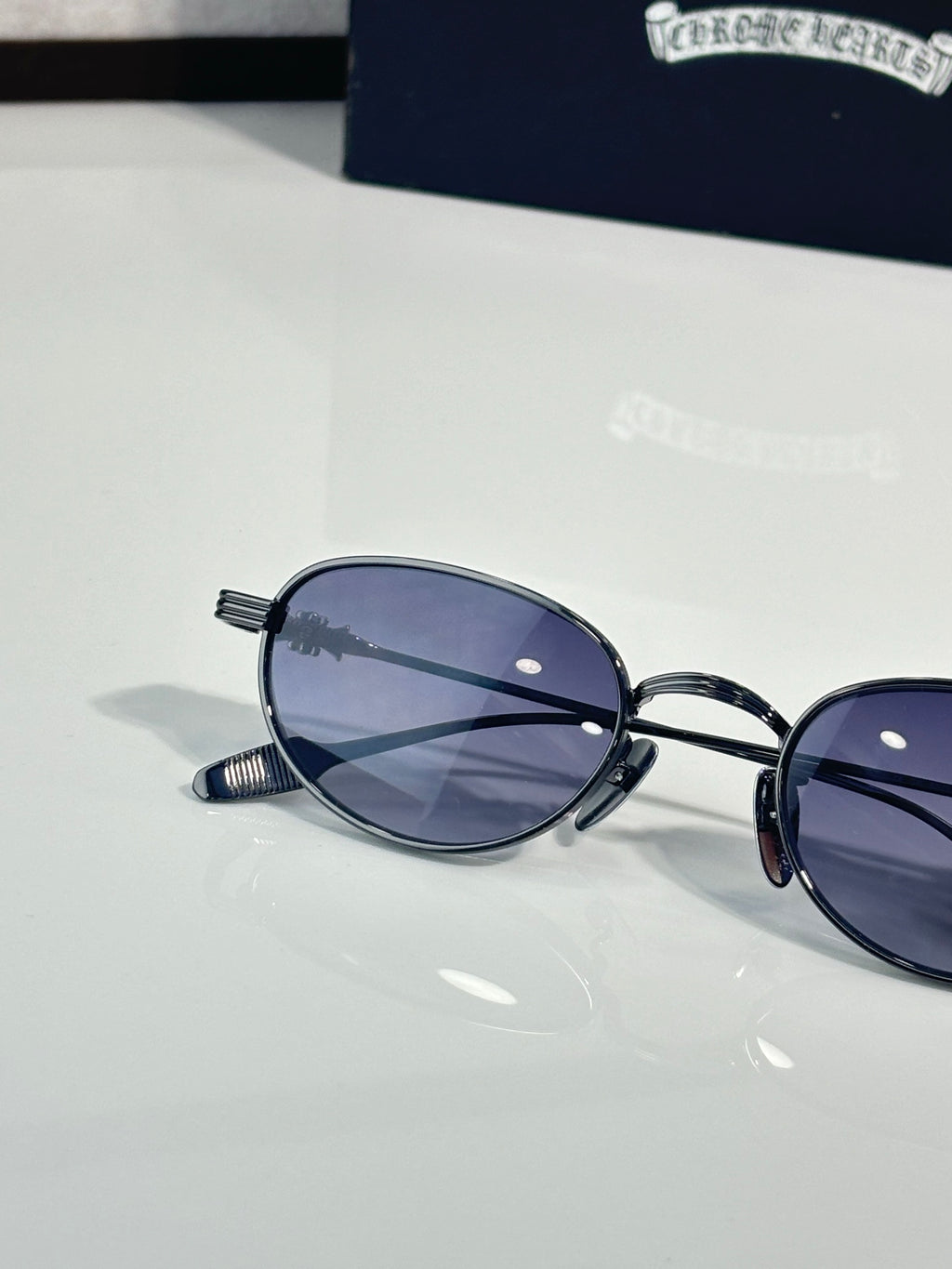 Oval lens sunglasses close-up with dark blue lenses and chrome metal arms