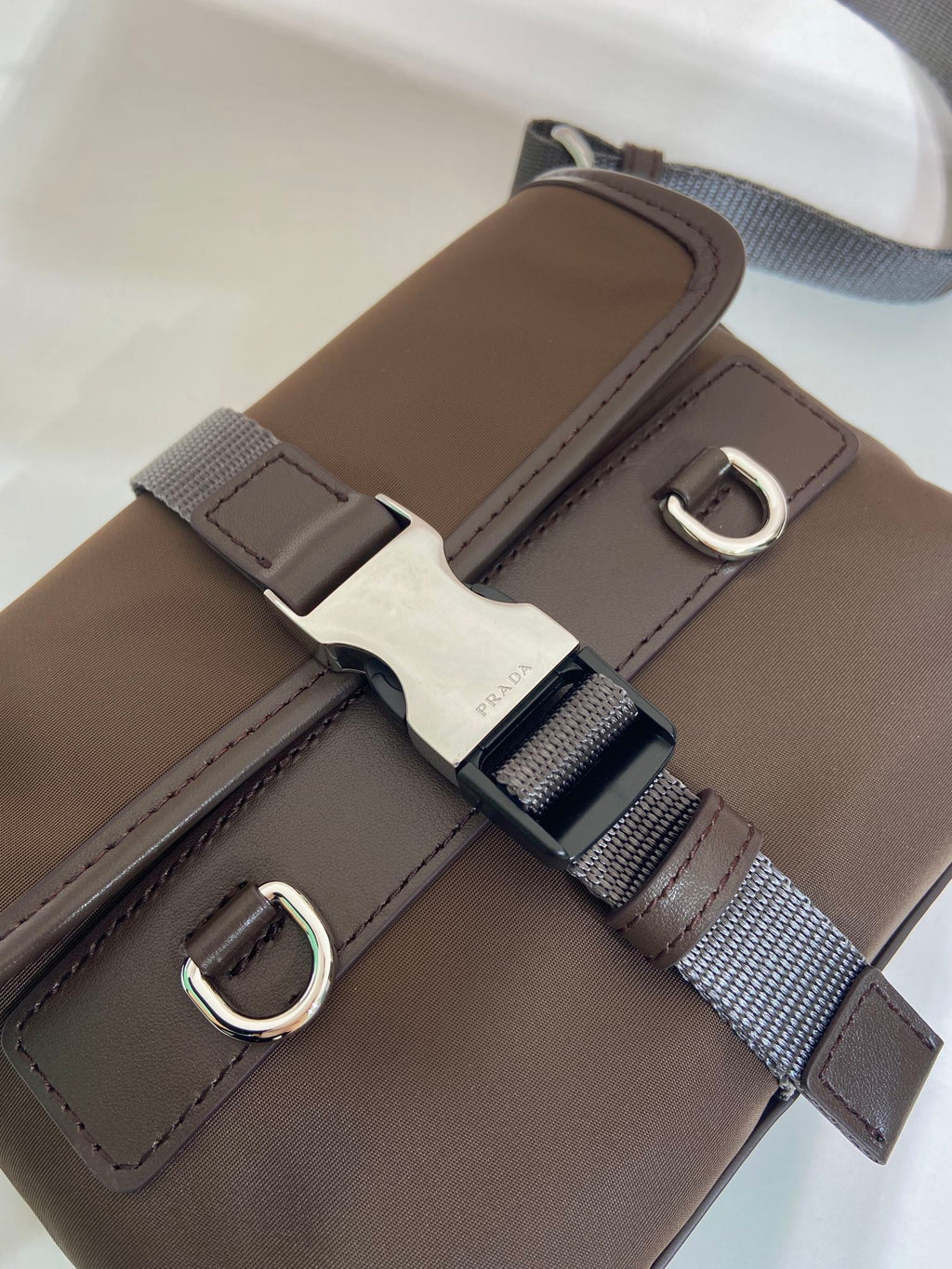 Prada brown nylon bag strap close-up with metal D-ring and buckle