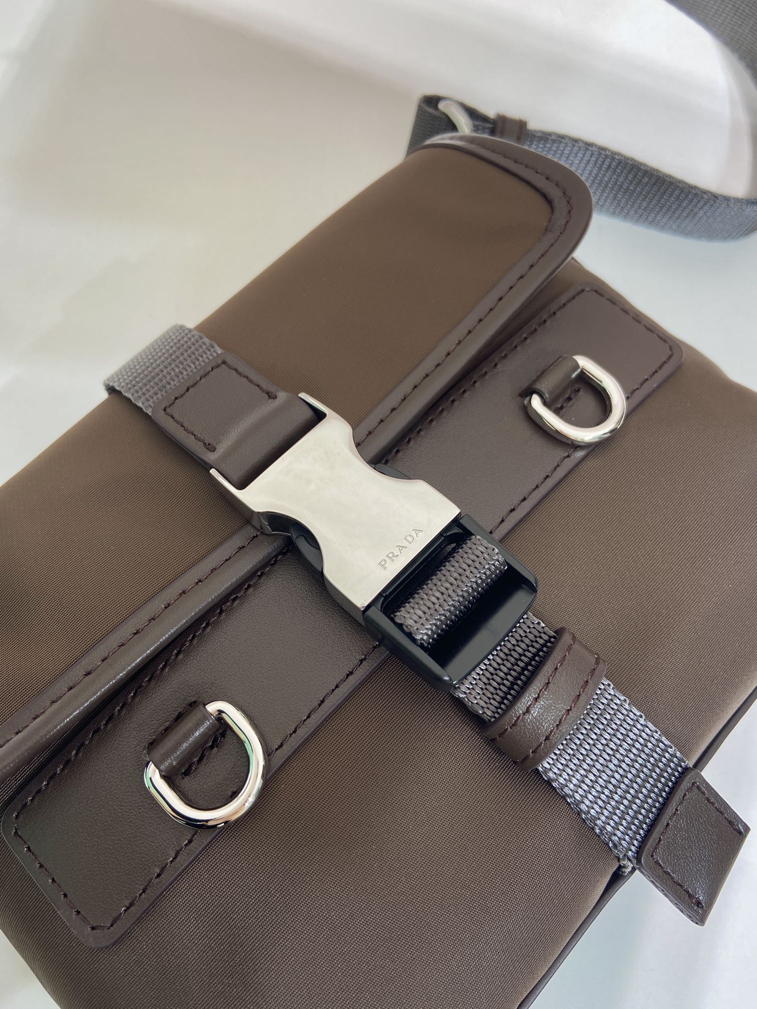Prada brown nylon bag strap close-up with metal D-ring and buckle