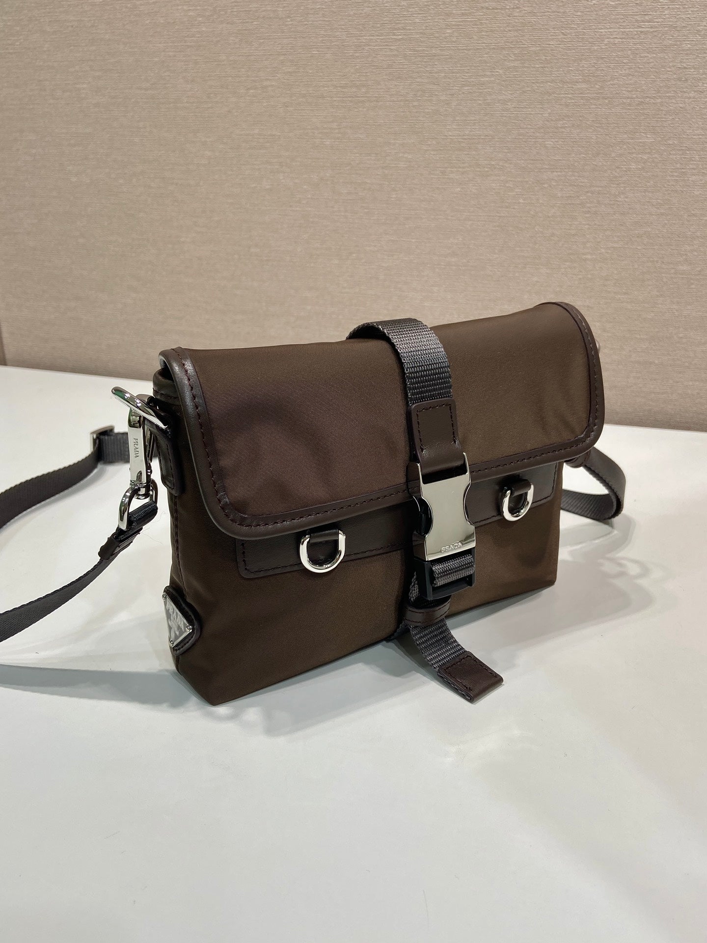 Prada dark brown nylon crossbody bag with flap, belt strap, and silver hardware