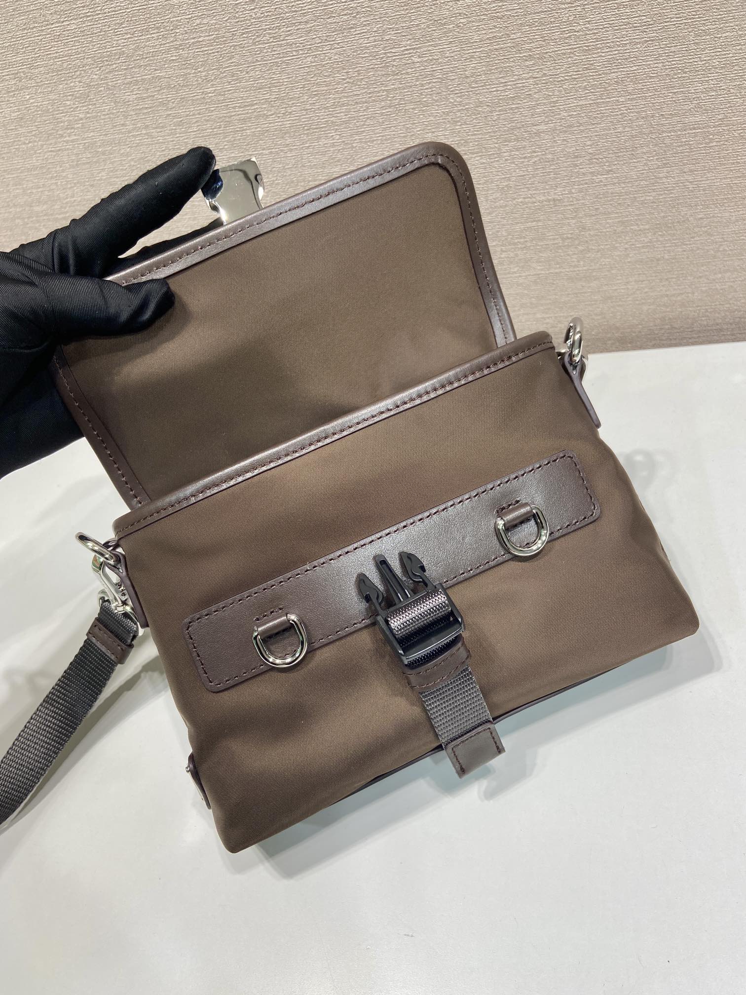 Prada brown nylon bag with front clasp, D-ring details, and adjustable strap