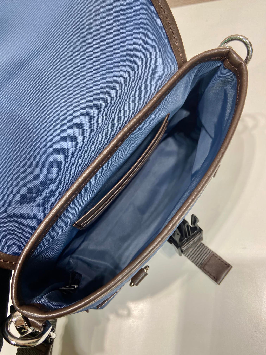Open blue crossbody bag interior with brown zipper trim and strap loop