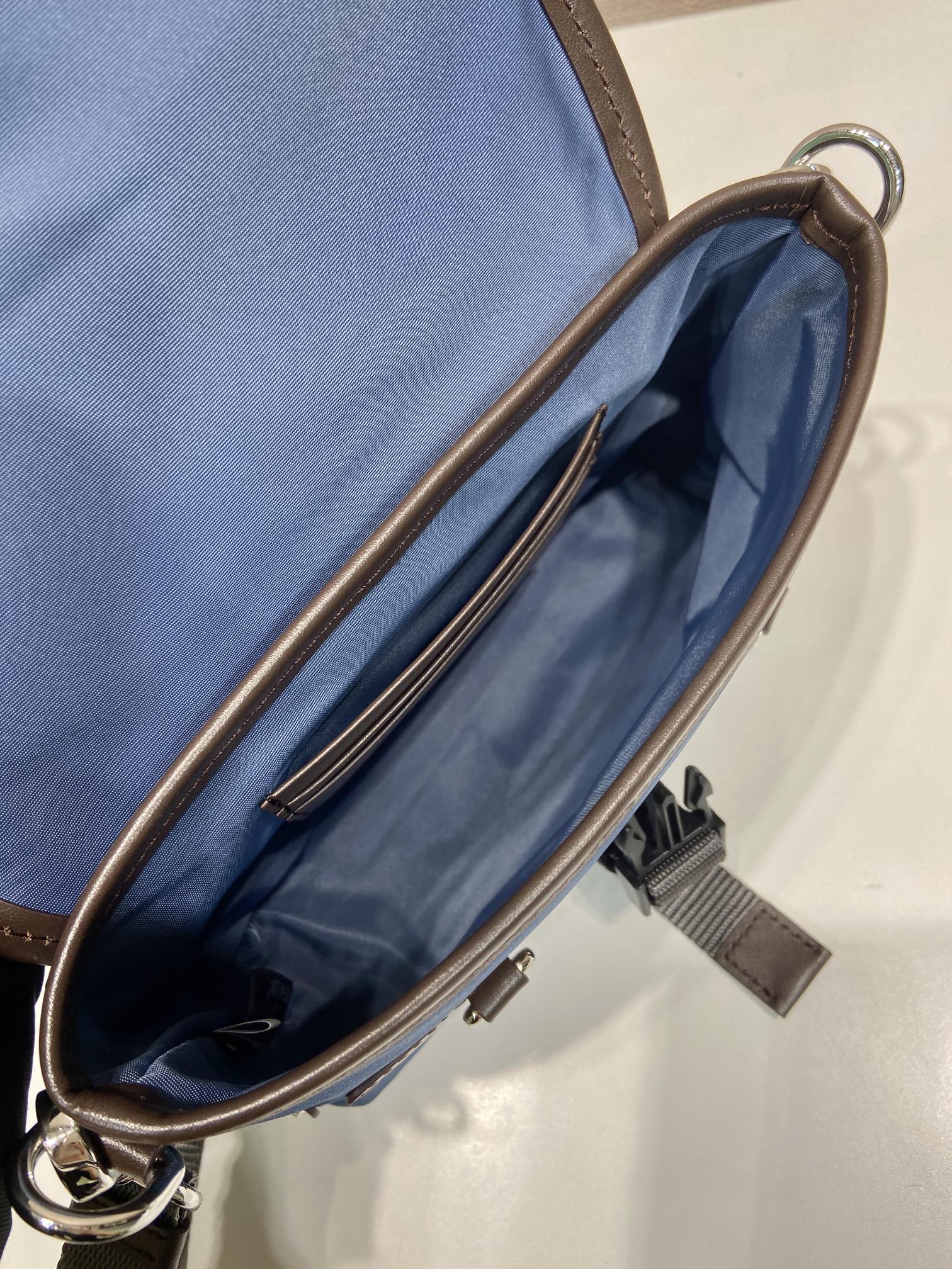 Open blue crossbody bag interior with brown zipper trim and strap loop
