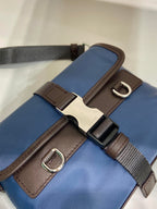 Close-up of blue bag strap with brown buckle hardware and metal D-rings