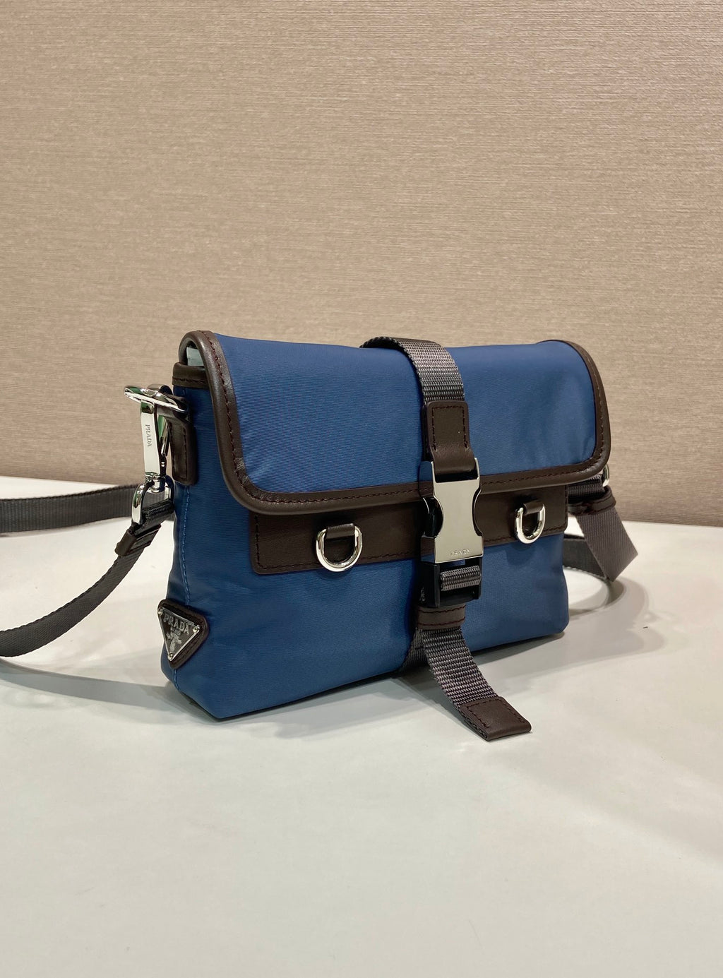 Blue crossbody bag with flap, brown trim, metal buckles, adjustable strap