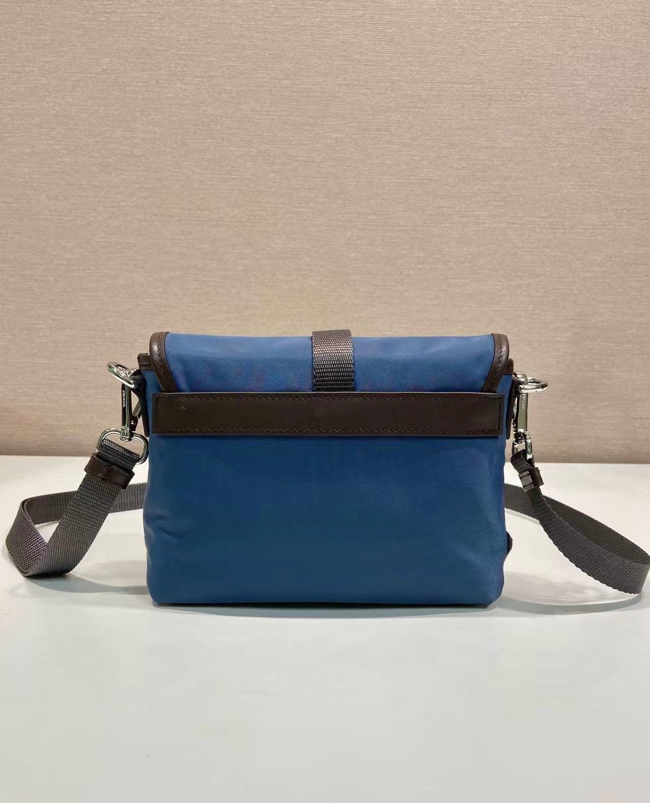 Blue crossbody bag with front flap, brown panel, side metal zipper pulls