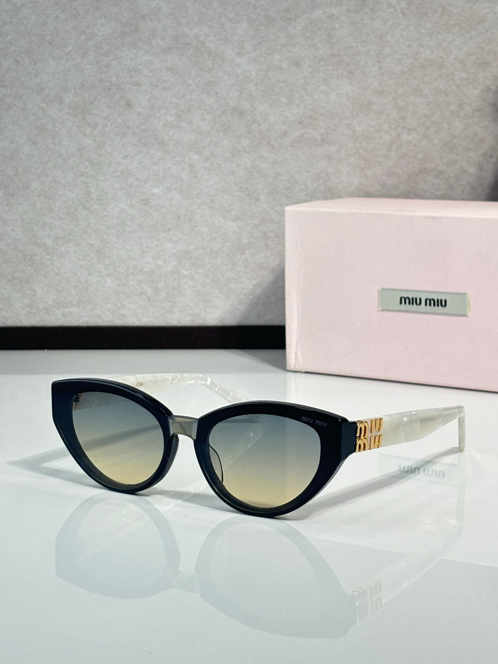 Cat-eye sunglasses with dark tortoiseshell frames, gold temple logo, tinted lenses