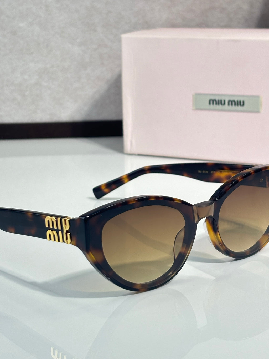 Cat-eye sunglasses angled view, dark tortoiseshell frame, tinted lenses, gold temple details