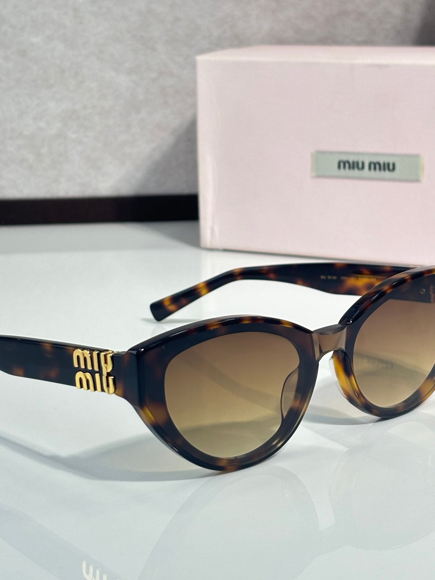 Cat-eye sunglasses angled view, dark tortoiseshell frame, tinted lenses, gold temple details