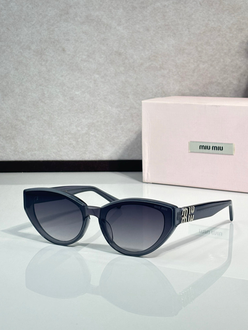 Cat-eye sunglasses with dark tortoiseshell frames and gold logo on temples, tinted lenses