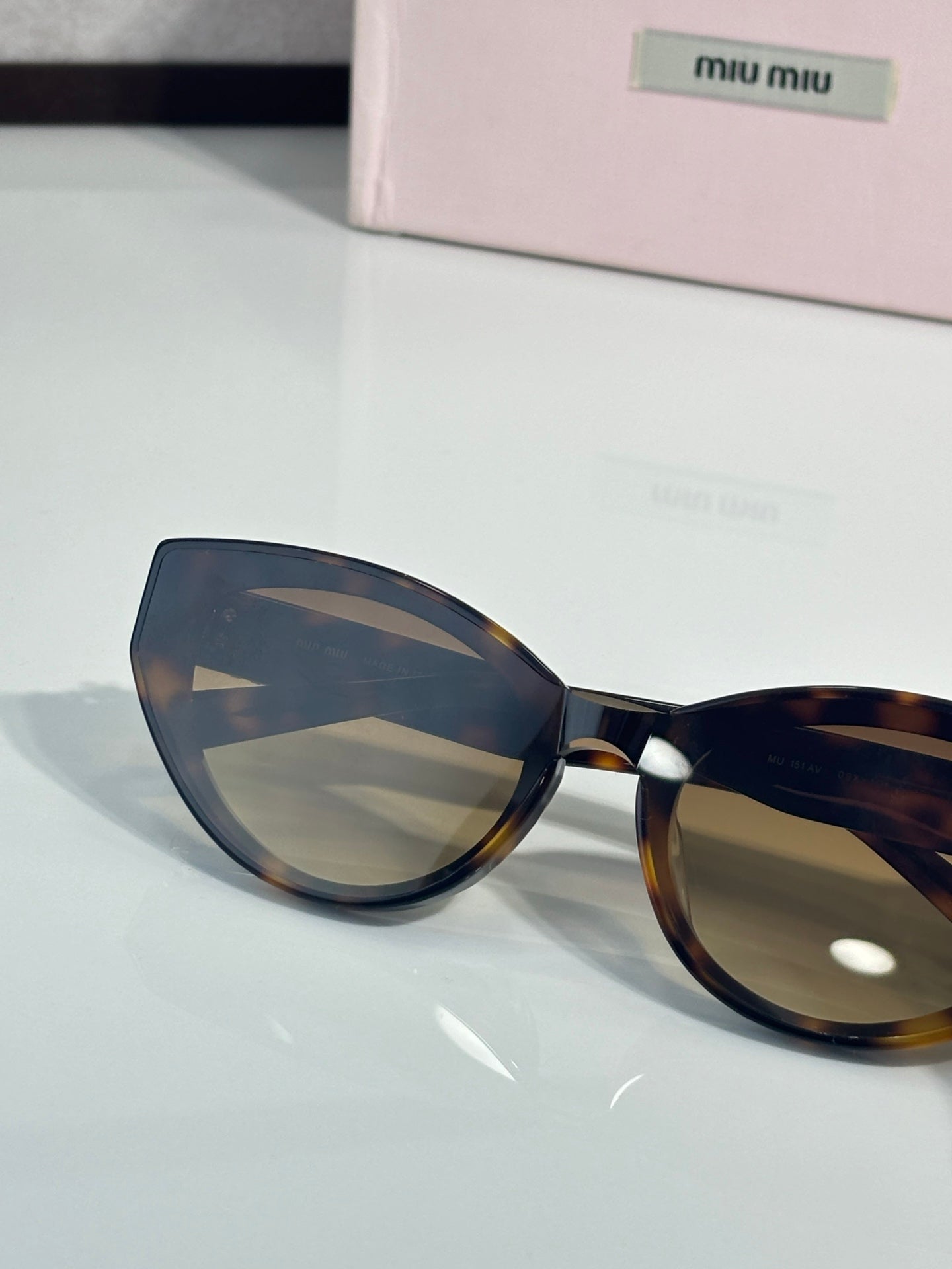 Cat-eye sunglasses close-up, dark tortoiseshell frame and tinted lenses, clear bridge
