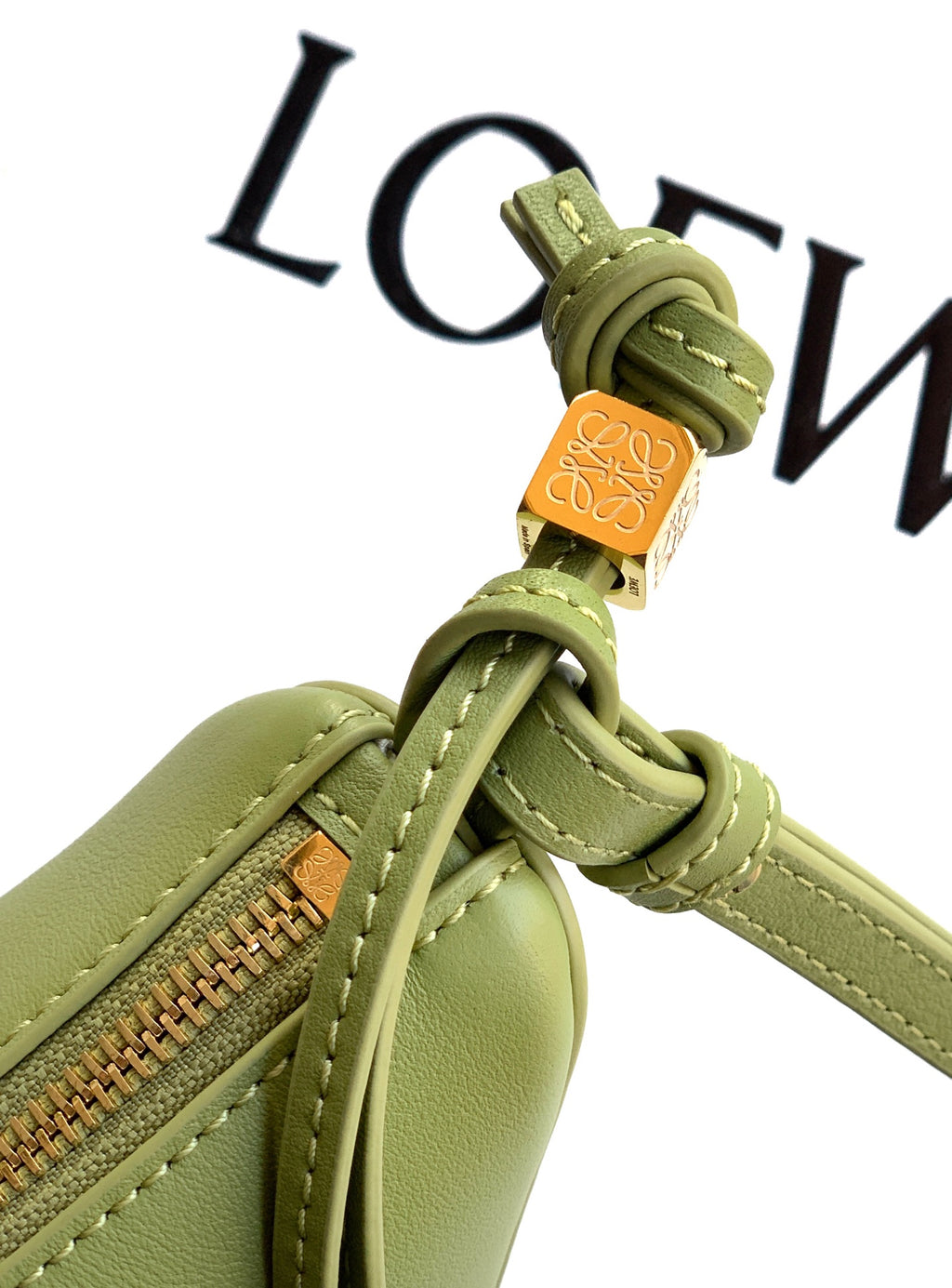Loewe lime green leather zipper pull close-up with braided strap knot and logo detail
