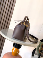 Dark brown leather top-handle bag with crossbody strap and gold-tone clasp hardware