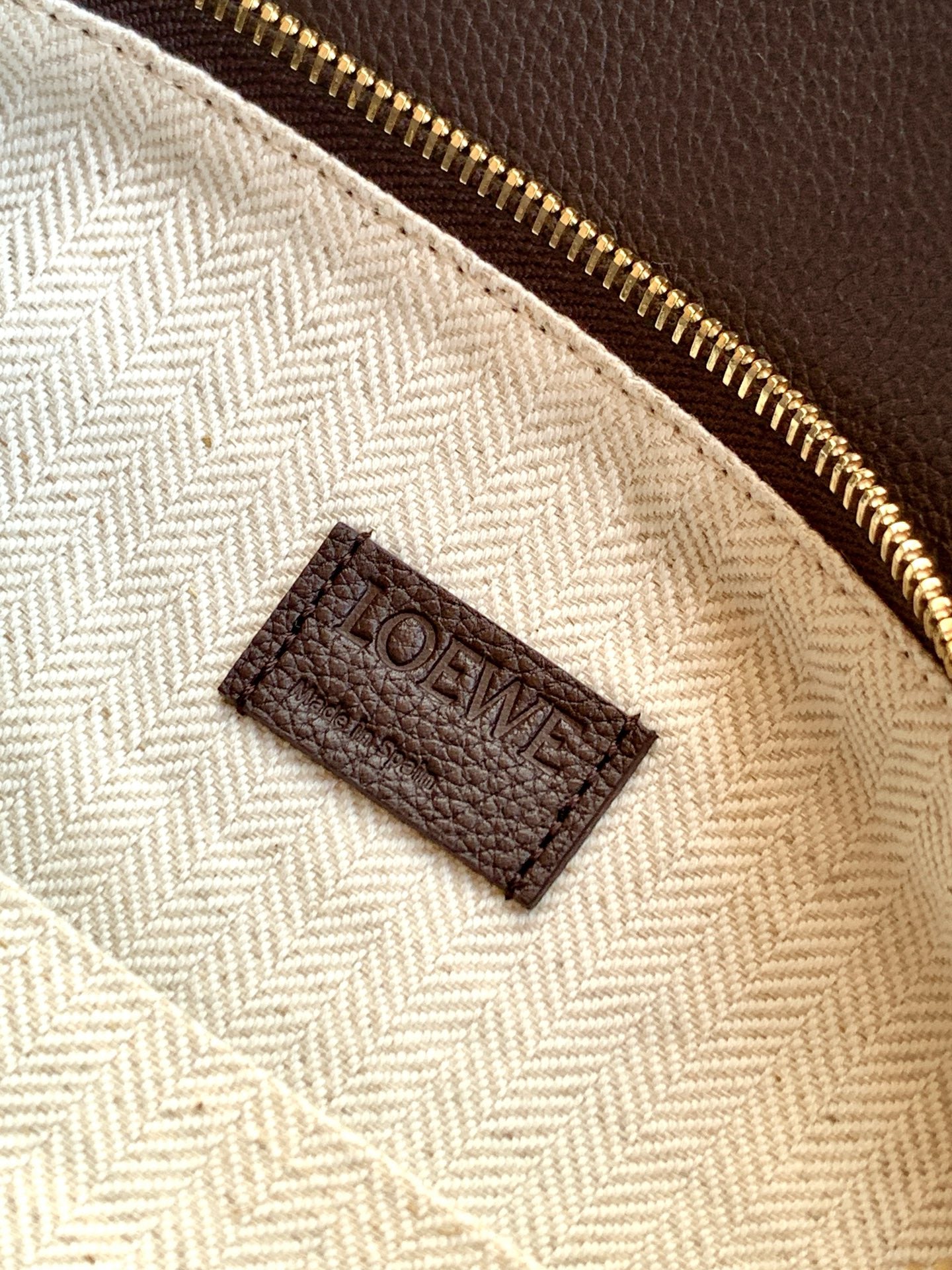Beige fabric pouch inside with dark brown LOEWE logo label and gold zipper