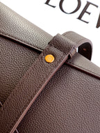 Dark brown leather bag corner with round gold-tone stud detail and folded strap