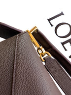 Dark brown leather bag corner with gold-tone clasp and zipper pull