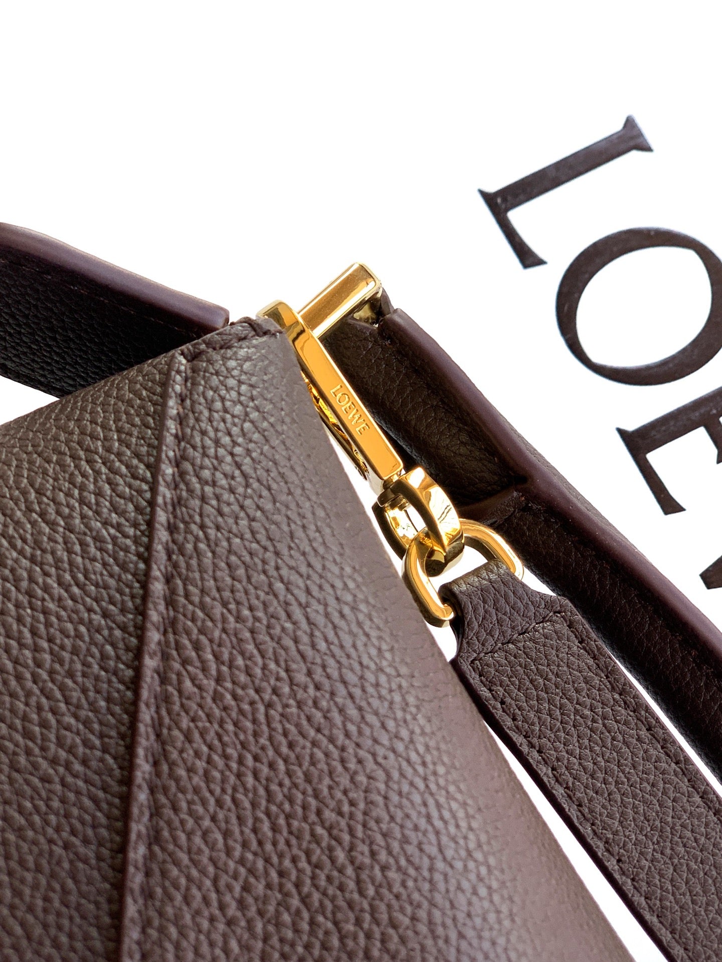 Dark brown leather bag corner with gold-tone clasp and zipper pull