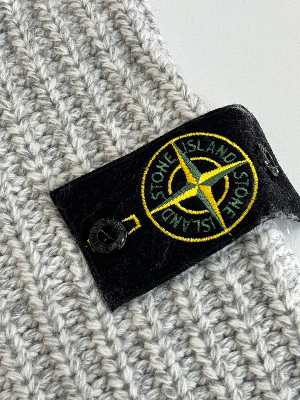 Stone Island woven neck label on light gray textured knit fabric