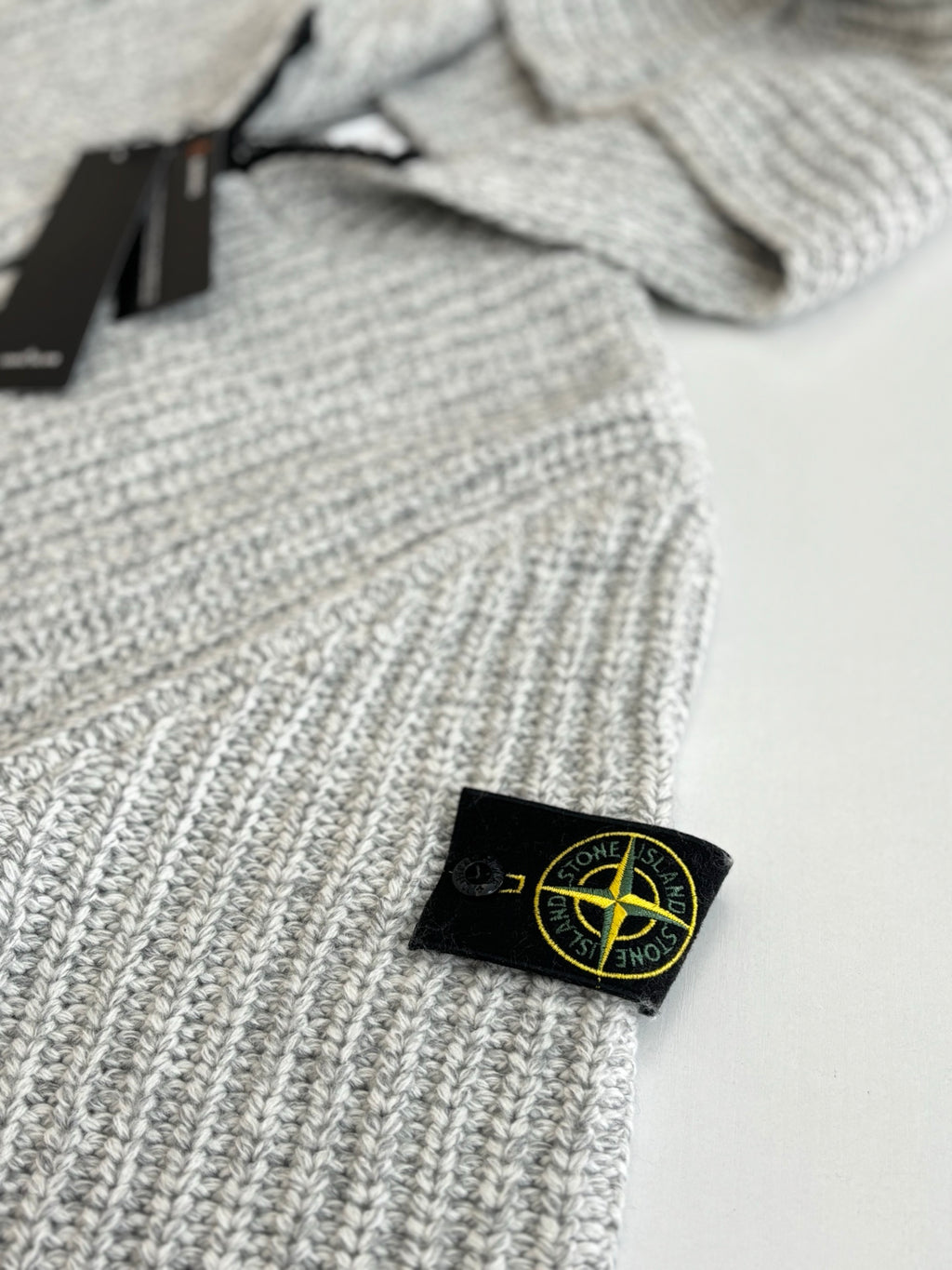 Stone Island knit hoodie chest label on light gray ribbed knit with black zipper trim