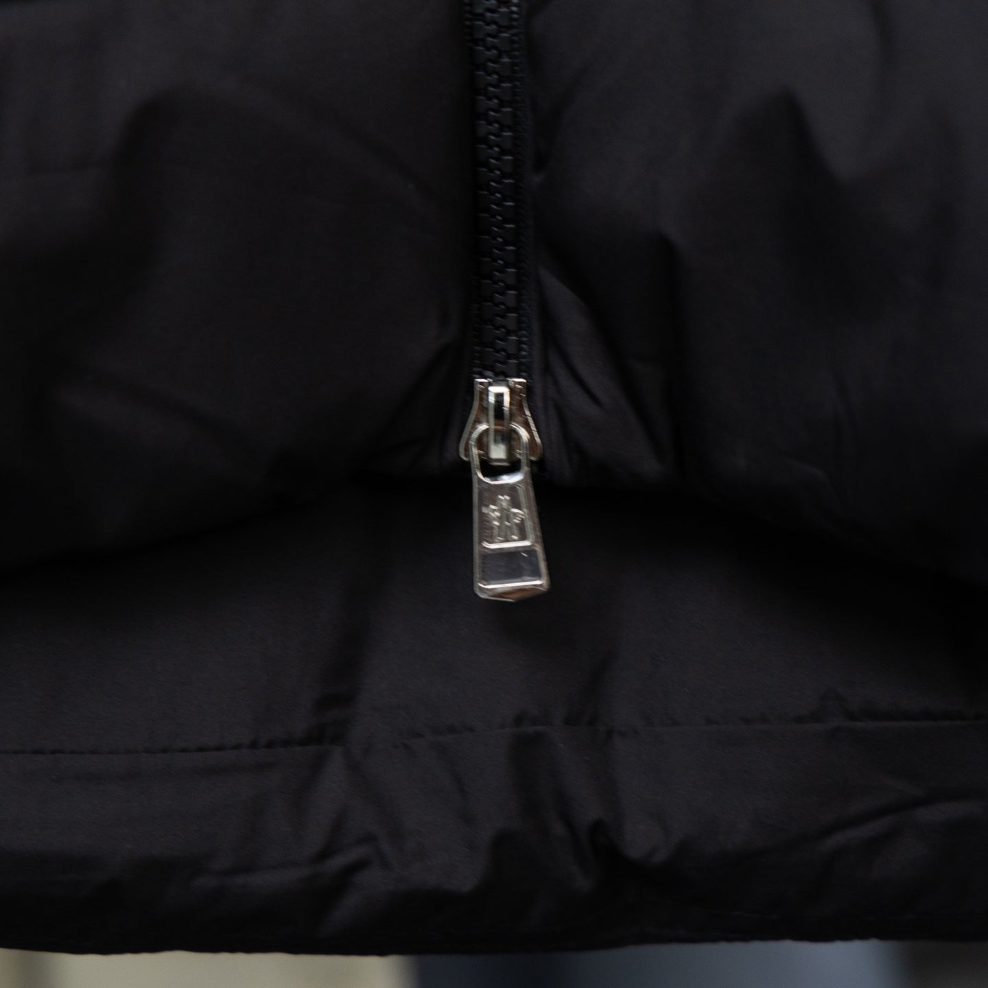 Long black puffer coat with front zipper close-up