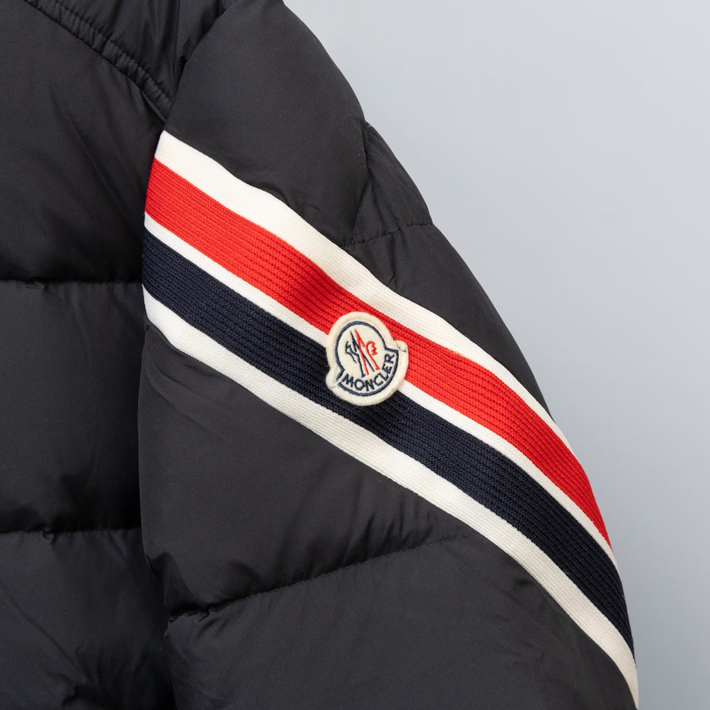 Black puffer jacket sleeve with red, white and navy striped band and crest logo