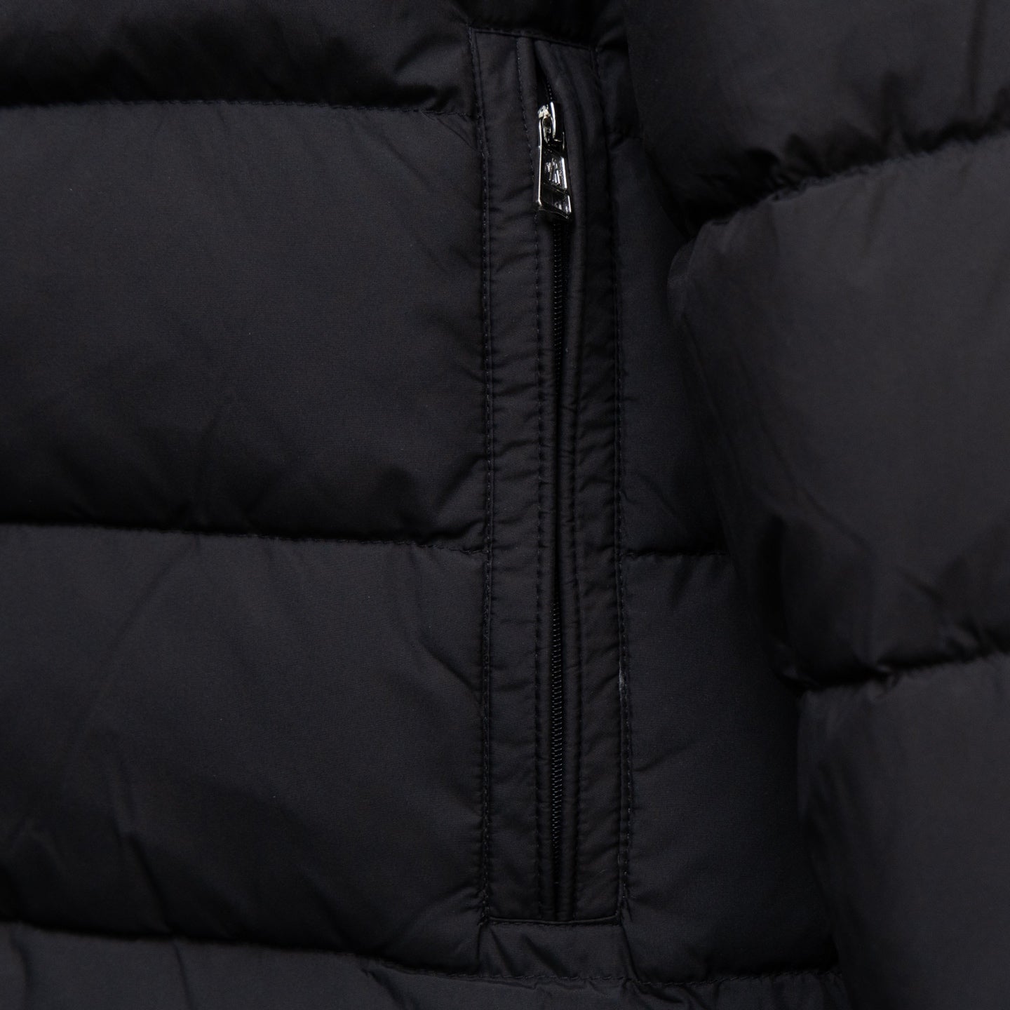 Black quilted puffer jacket front panel with centered zipper and stitched seams