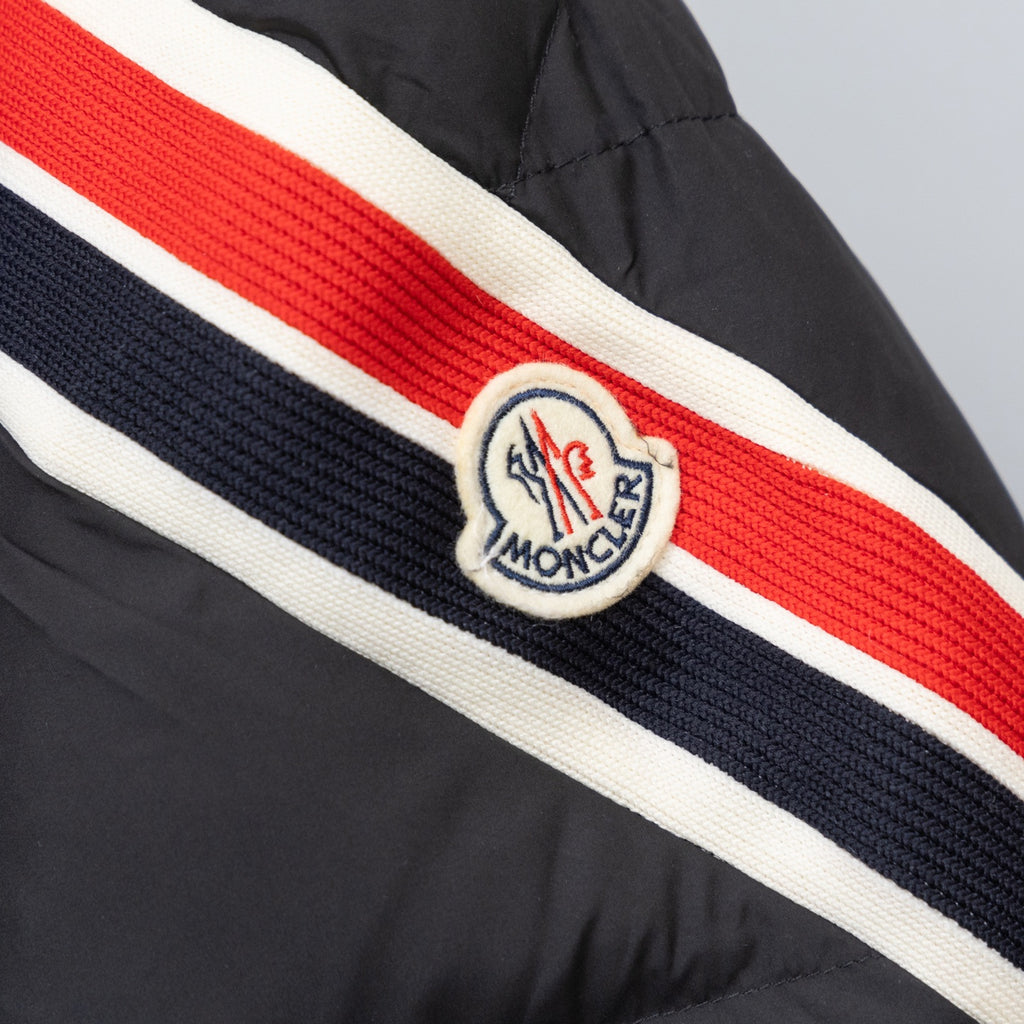 Striped band on black puffer jacket sleeve with crest logo in red and navy