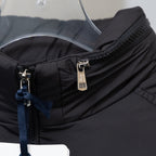Black puffer jacket front with metal zipper and stand collar, blue pull detail