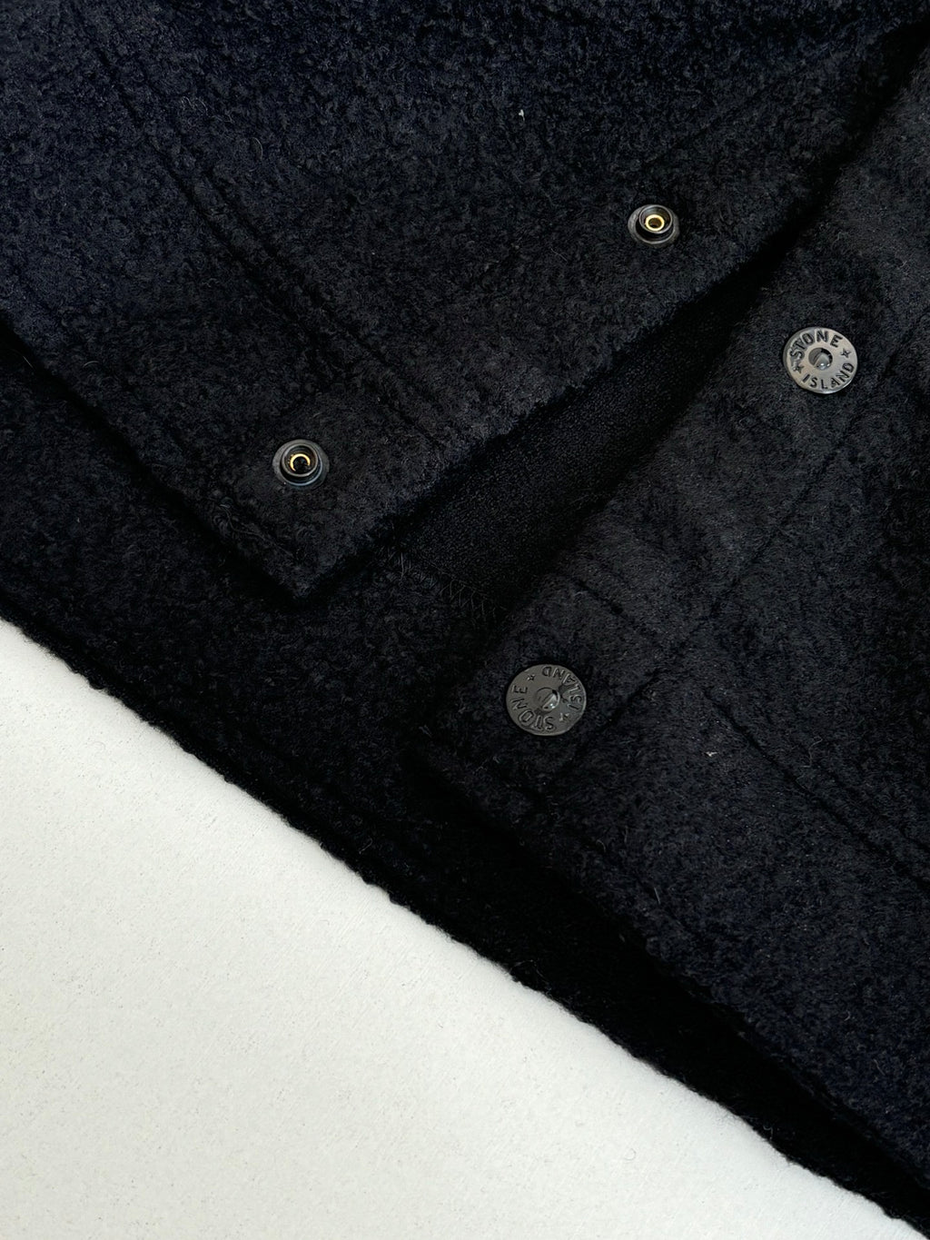 Dark jacket neckline with metal buttons and textured fabric