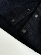 Dark jacket neckline with metal buttons and textured fabric