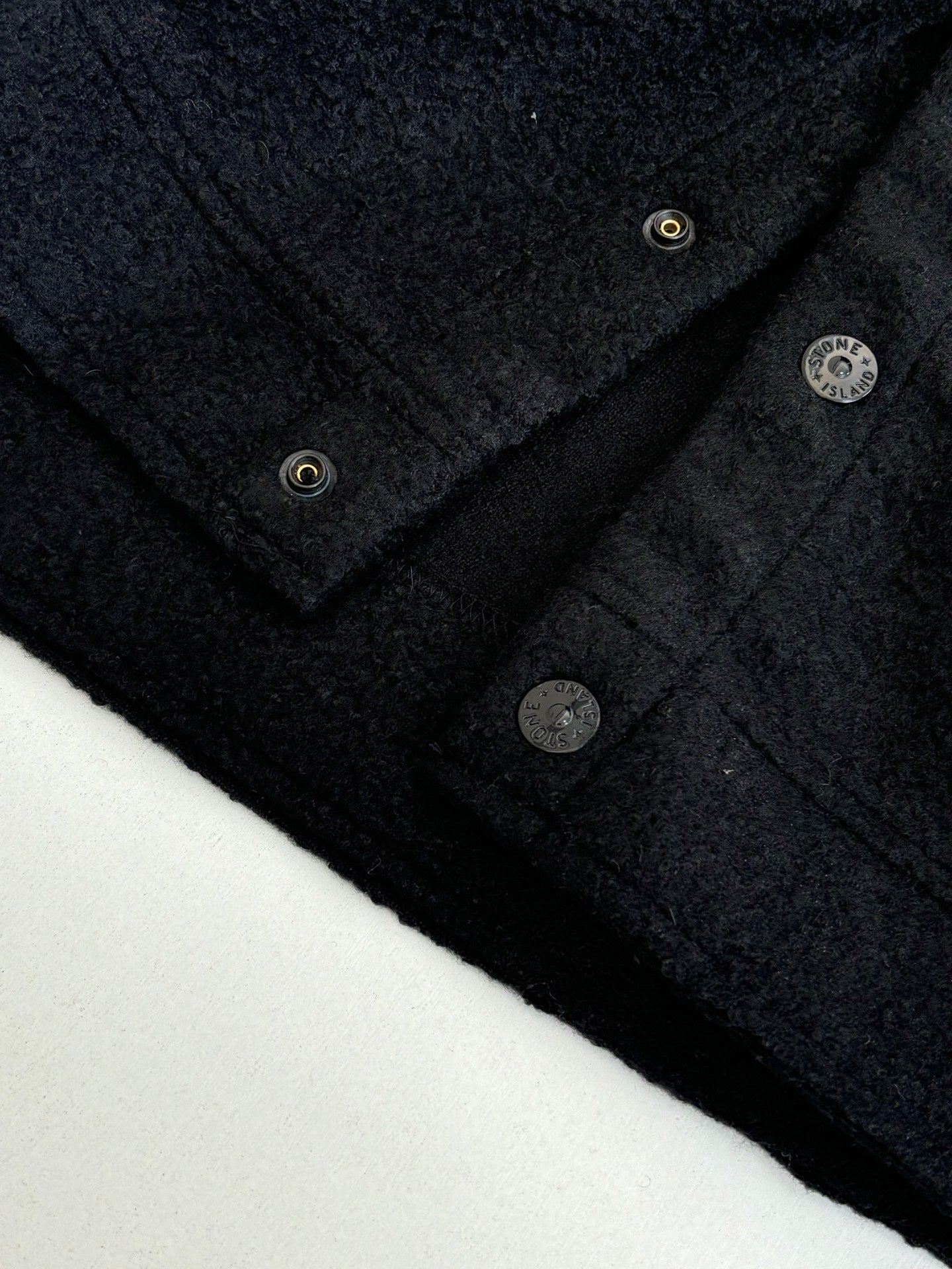 Dark jacket neckline with metal buttons and textured fabric