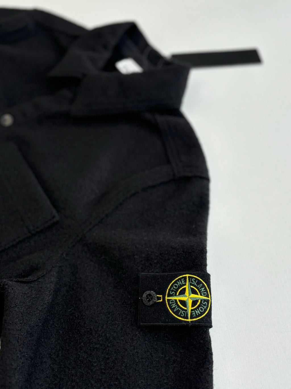 Dark jacket shoulder and chest with Stone Island logo patch